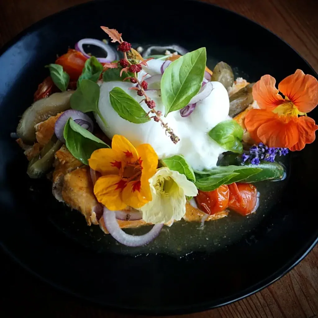 Keto Haehnchen mit geschmolzenen Tomaten und Burrate1 Zart gegrilltes Hähnchen aus dem Woodfire-Ofen, kombiniert mit geschmolzenen Tomaten, cremiger Burrata und frischen Kräutern. Edle Blüten sorgen für Farbe, Aroma und einen Hauch Raffinesse. Dieser Keto-Teller ist nicht nur Low Carb, sondern auch ein echtes Geschmackserlebnis für alle, die Feuer, Rauch und Frische lieben.